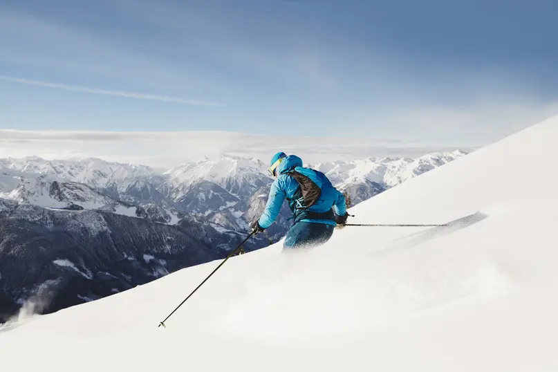 Tiefschnee-Skifahren im Zillertal Skifahrer im Tiefschnee oberhalb des Zillertals mit beeindruckendem Alpenpanorama.