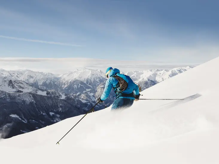 Tiefschnee-Skifahren im Zillertal Skifahrer im Tiefschnee oberhalb des Zillertals mit beeindruckendem Alpenpanorama.